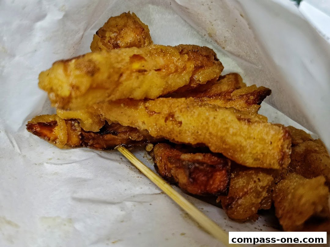 Close-up of crispy fried Taiwanese snacks served in a paper bag with a wooden skewer.