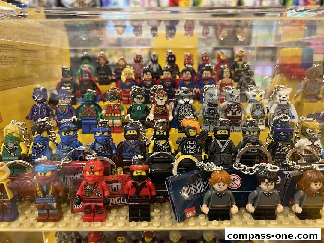 A display case filled with various LEGO minifigure keychains, including DC Comics and Ninjago characters.
