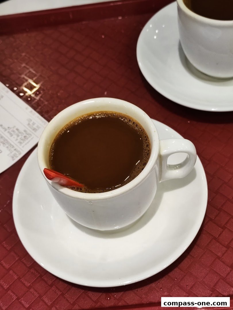 A close-up of a steaming cup of coffee with a red stirrer on a saucer.