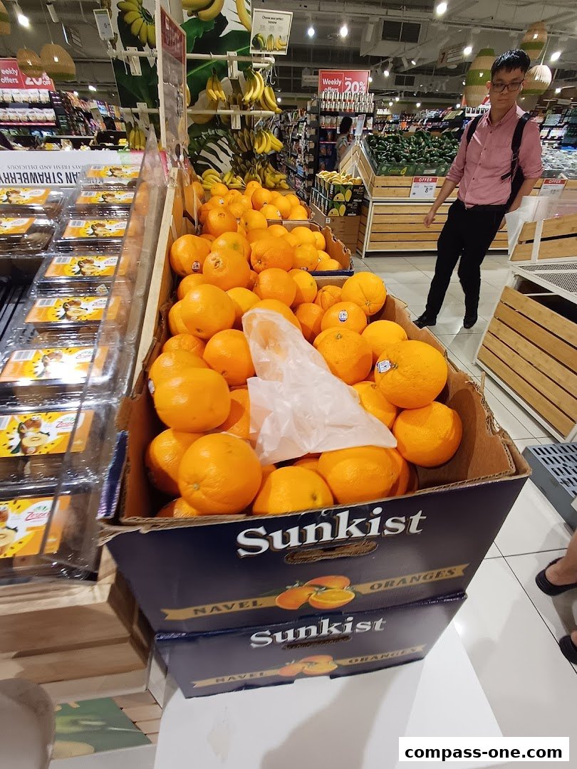 A display of Sunkist Navel Oranges and other fruits in a supermarket aisle.