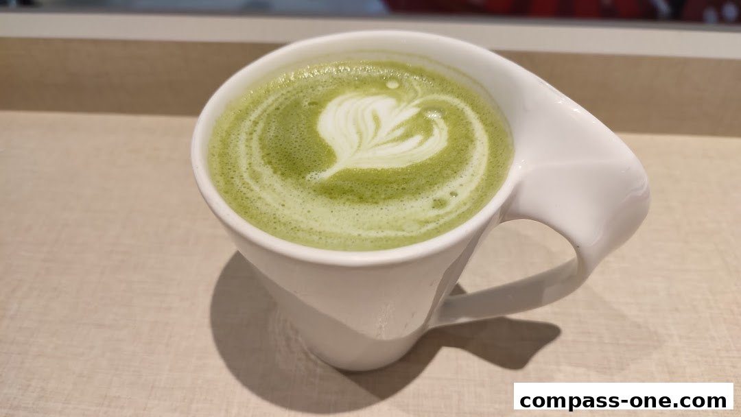 A close-up of a matcha latte with latte art in a white mug.