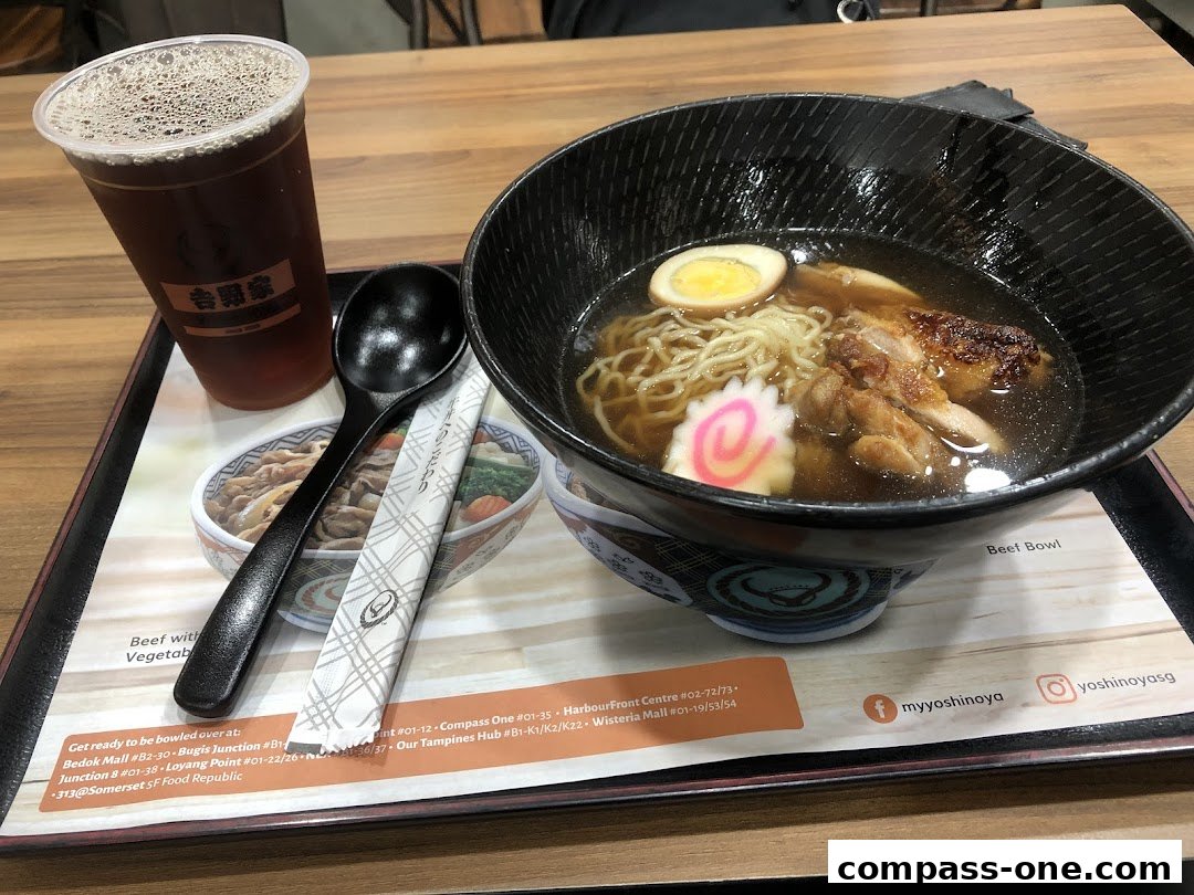 A bowl of ramen with chicken and a side of iced tea on a tray.