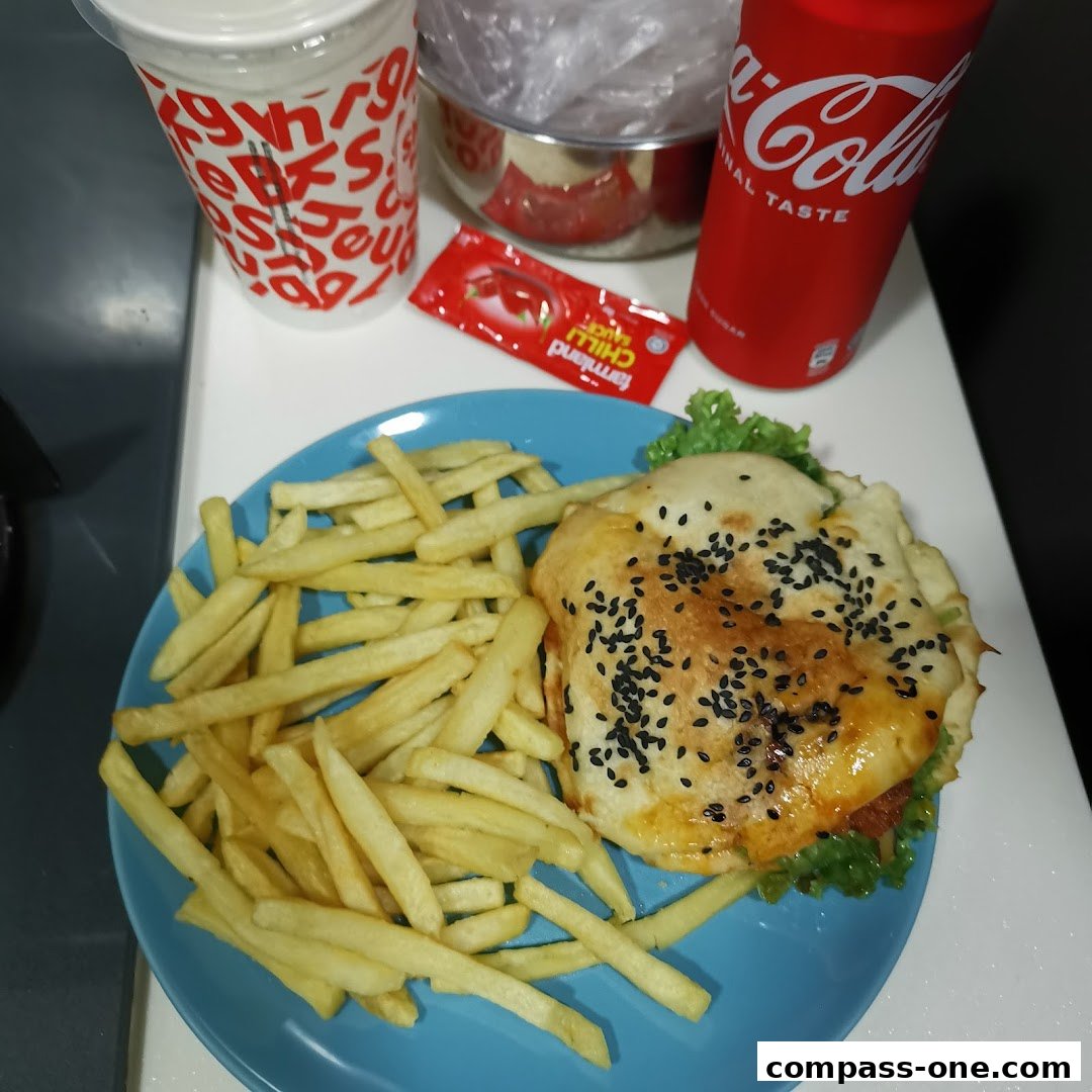 A delicious burger meal with fries, a drink, and chili sauce.