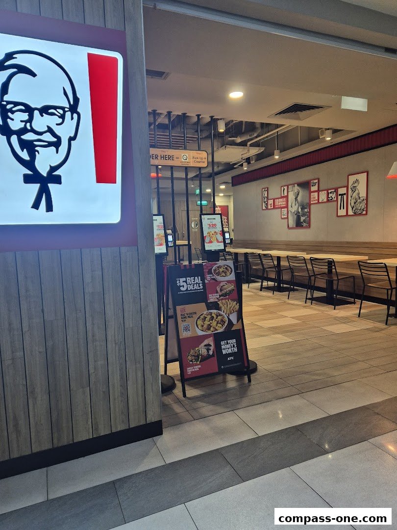 The entrance to a KFC restaurant with its iconic Colonel Sanders logo and a promotional sign.