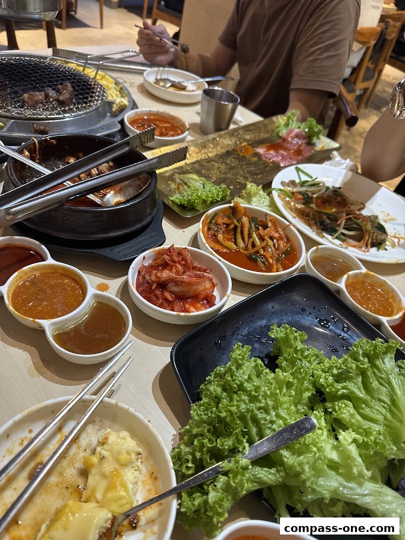 A table laden with Korean BBQ dishes, including grilled meat, kimchi, and lettuce wraps.