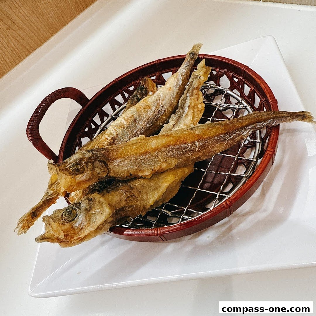 A basket of golden-brown fried smelt fish served on a white plate.