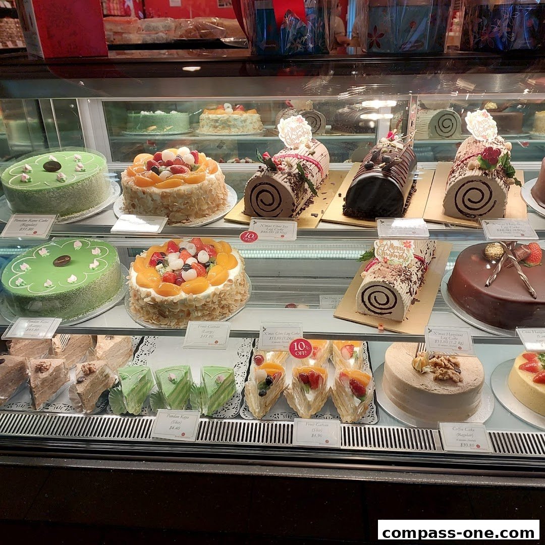 A display case filled with various cakes, including log cakes, round cakes, and sliced cakes.