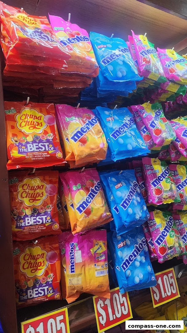 A display of assorted candies, including Chupa Chups and Mentos, on shelves with price tags.