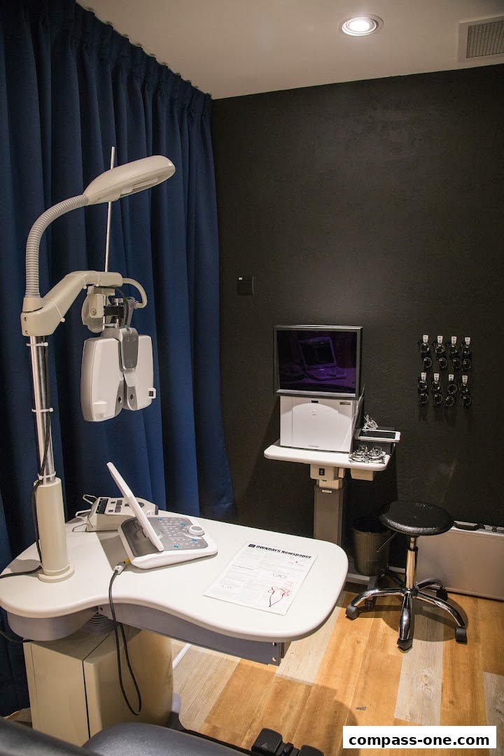 An eye examination room with specialized equipment and a stool.