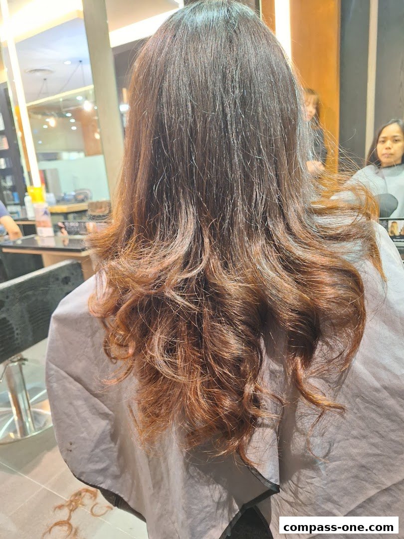 A person's back with freshly styled, wavy brown hair in a salon.