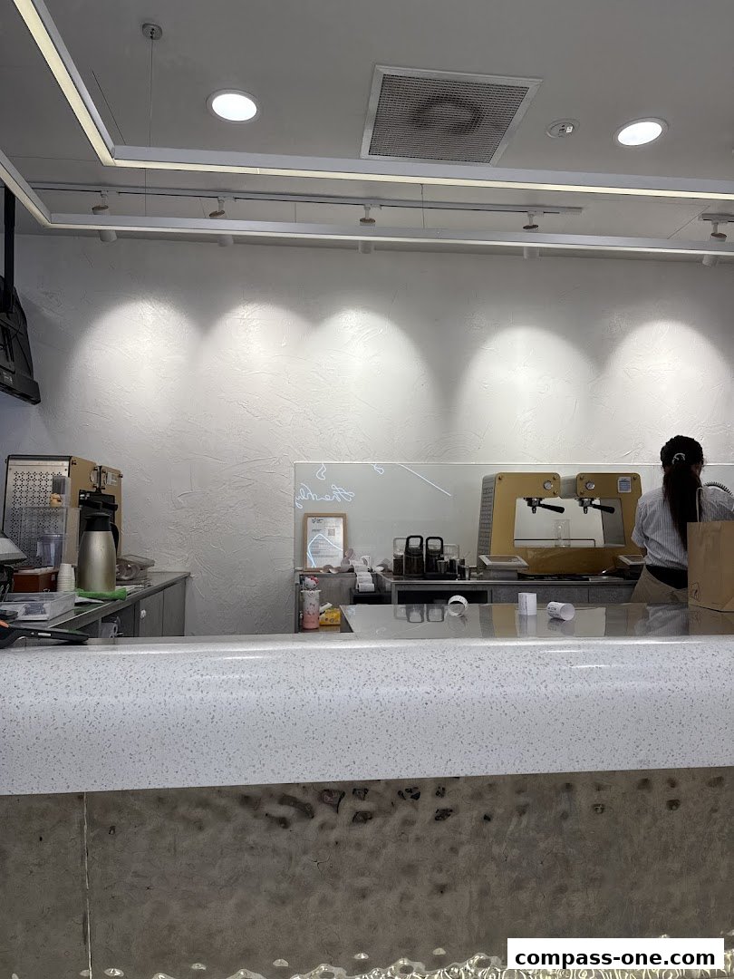 Interior view of a modern beverage shop counter with staff preparing drinks.