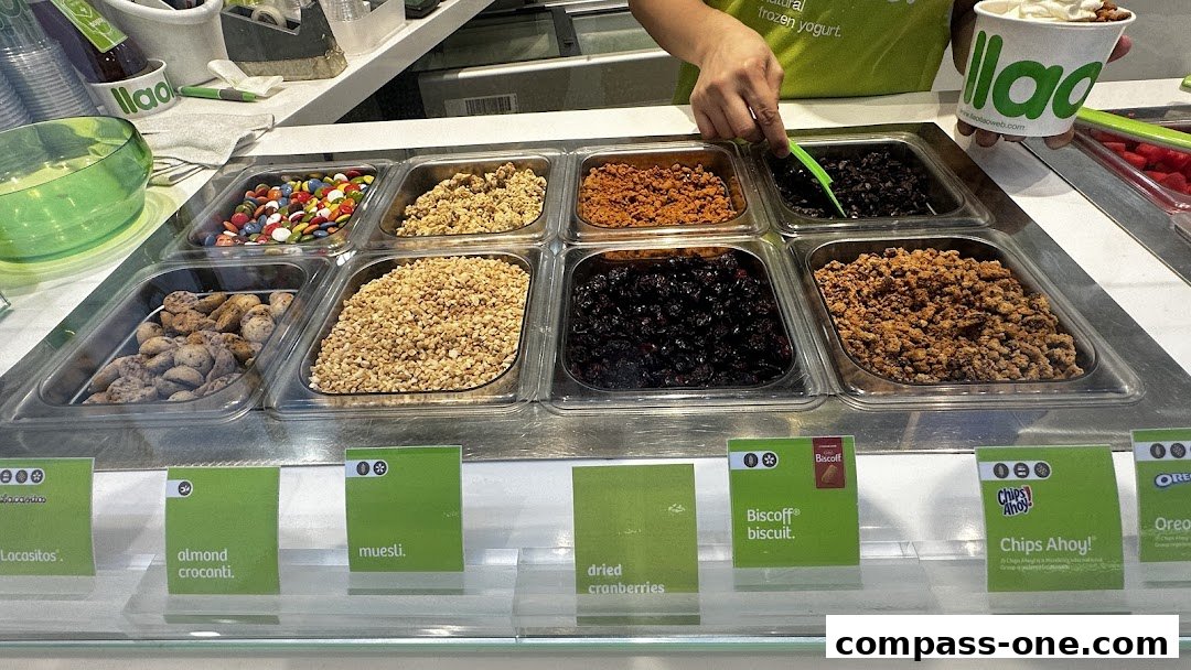 A display of frozen yogurt toppings including candies, nuts, and cookies at llaollao.