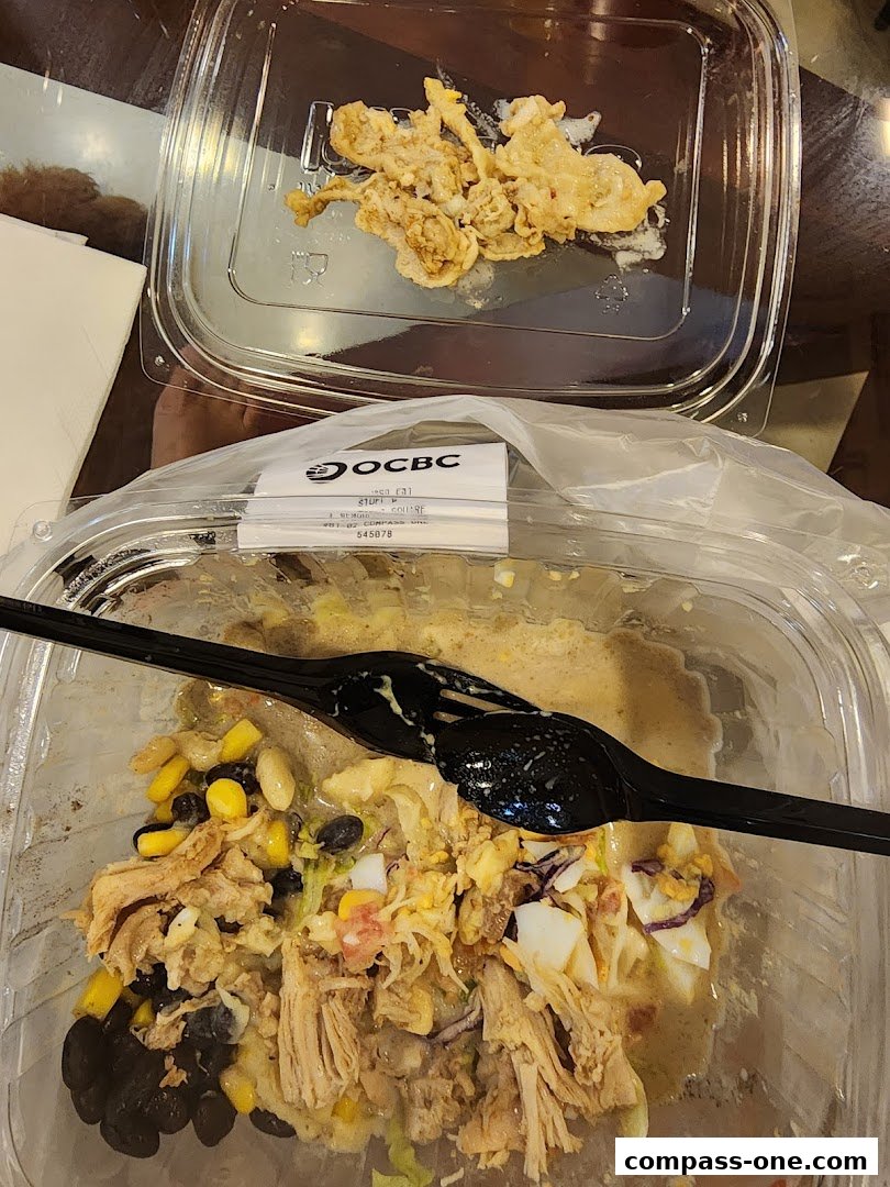 A partially eaten salad in a clear plastic container with a black fork and spoon.