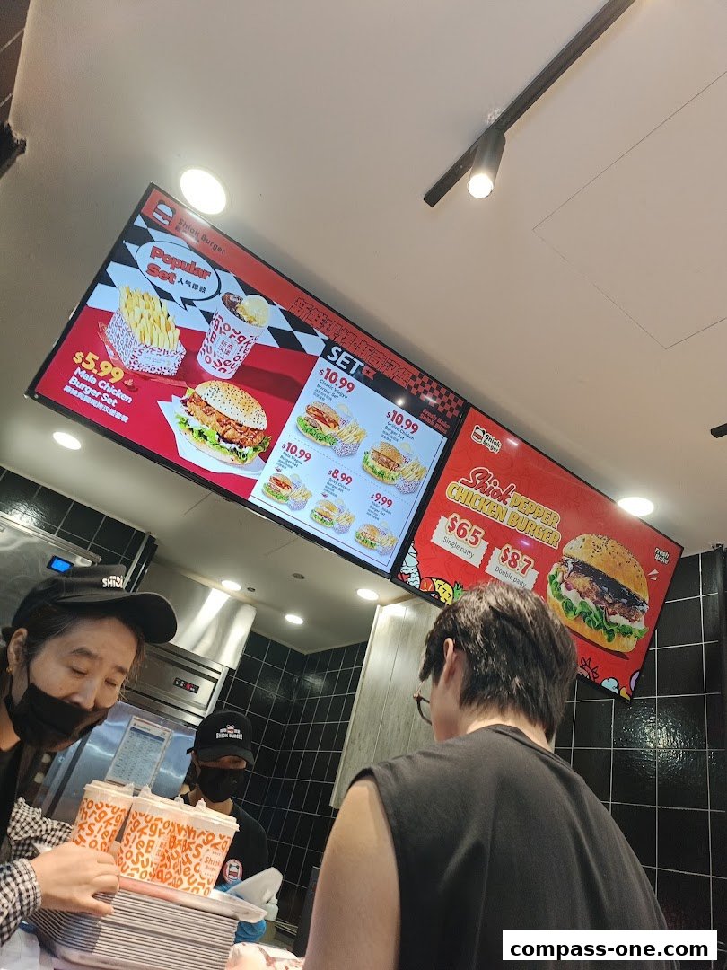 A digital menu board displays various burger sets and individual burgers with prices.