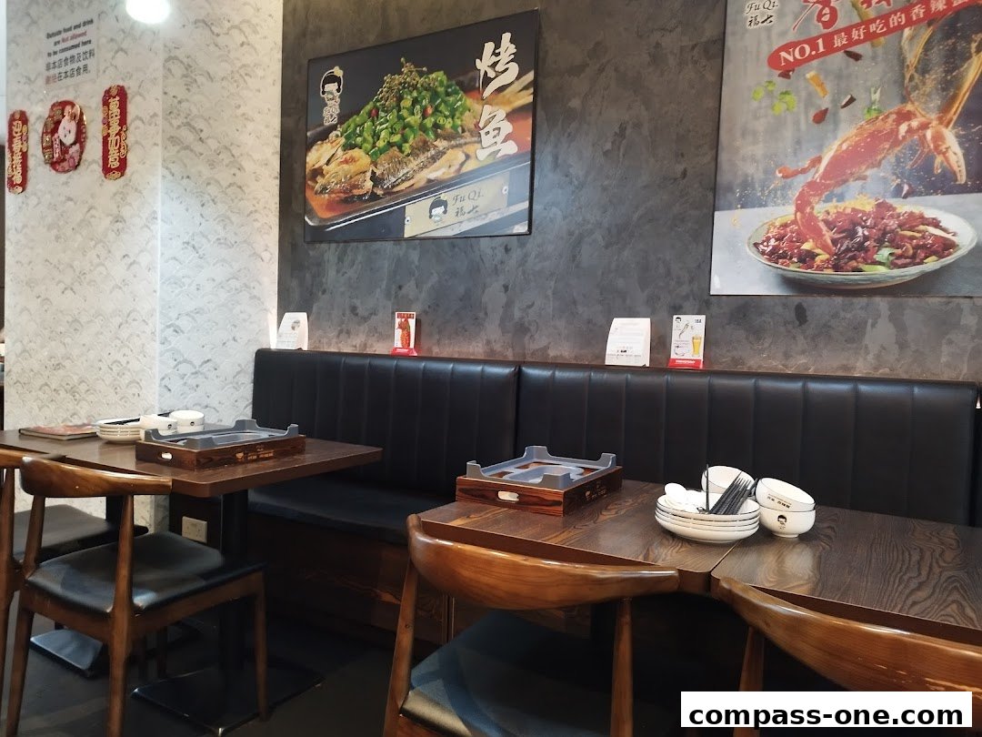 Interior of a restaurant with tables, chairs, and posters of food.