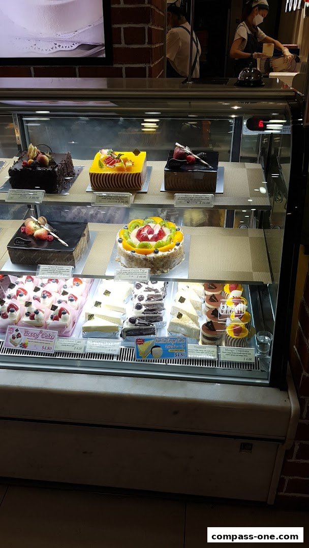 A display case filled with various cakes and pastries from the Four Leaves bakery.