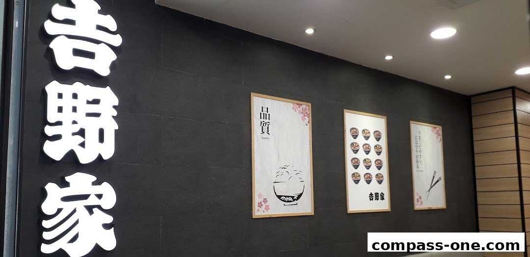 Yoshinoya shop interior with large Japanese characters and framed artwork on a dark wall.