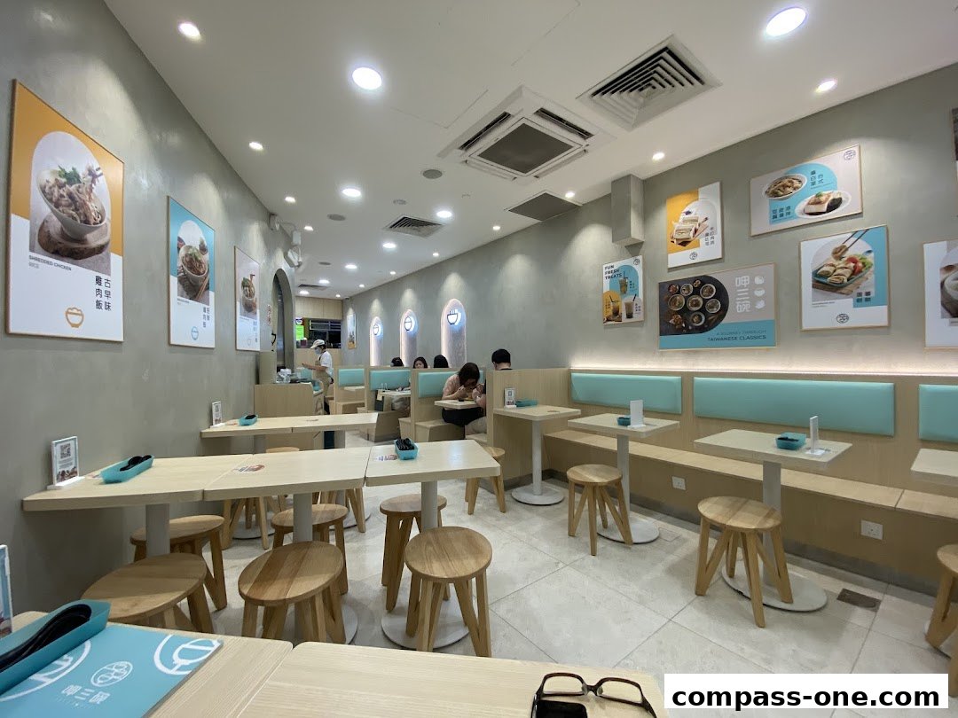 Interior view of a clean and modern Taiwanese restaurant with wooden tables and stools.