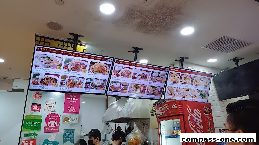 Digital menu boards displaying various set meals and side orders at a food stall.