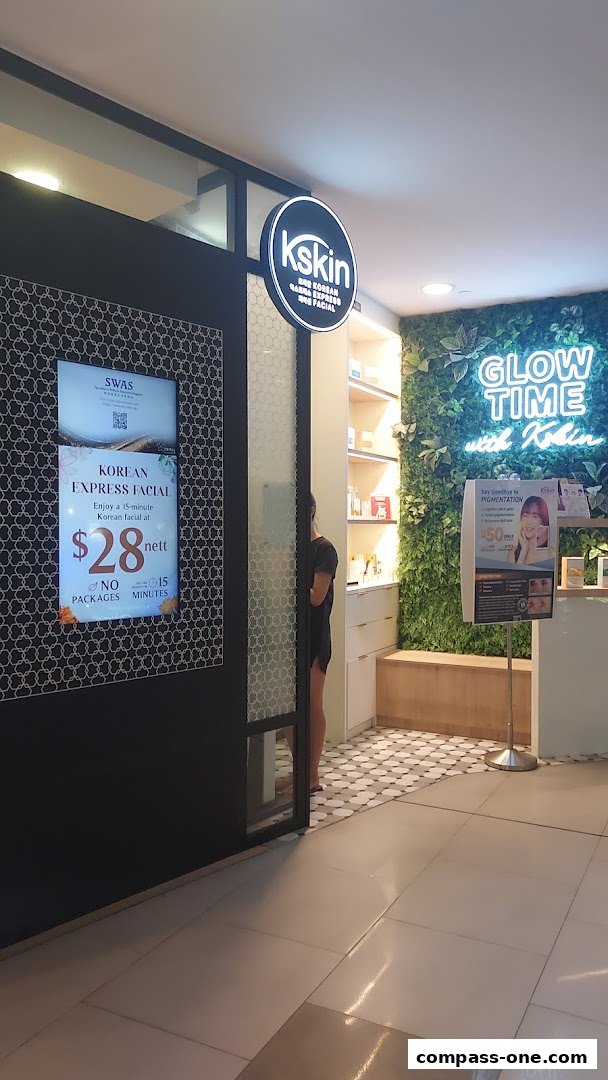The entrance of Kskin Korean Express Facial with promotional displays and a green wall.