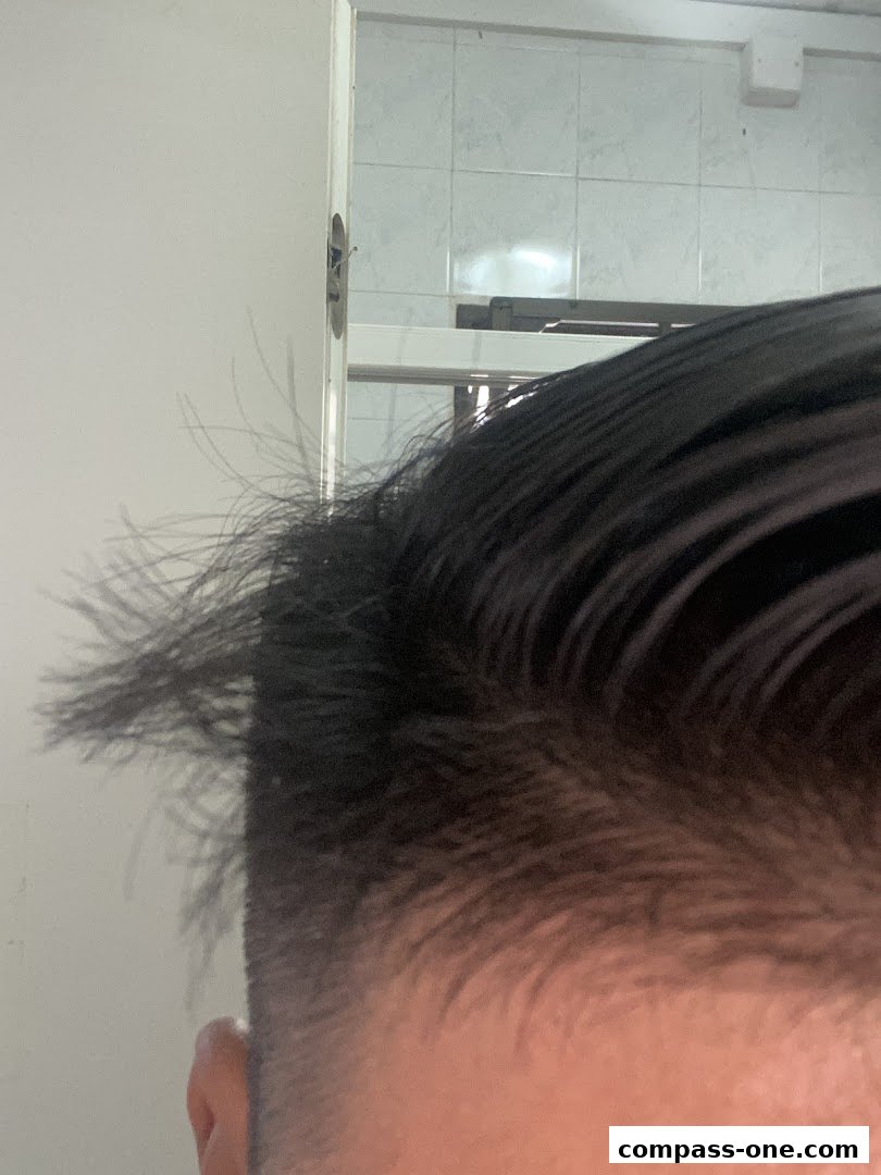 Close-up of a person's hair and ear, with a tiled wall and door in the background.