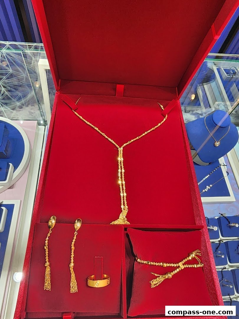 A red jewelry box displaying a gold necklace, earrings, ring, and bracelet.