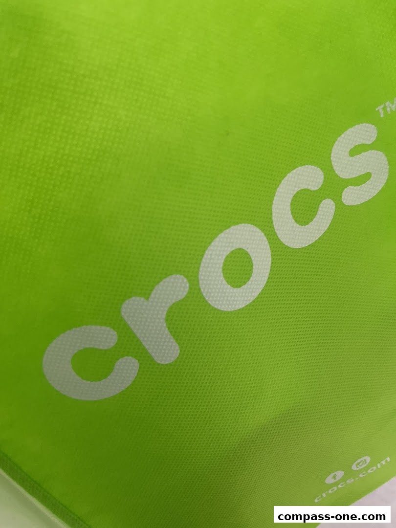 A bright green bag with the white Crocs logo and website address.