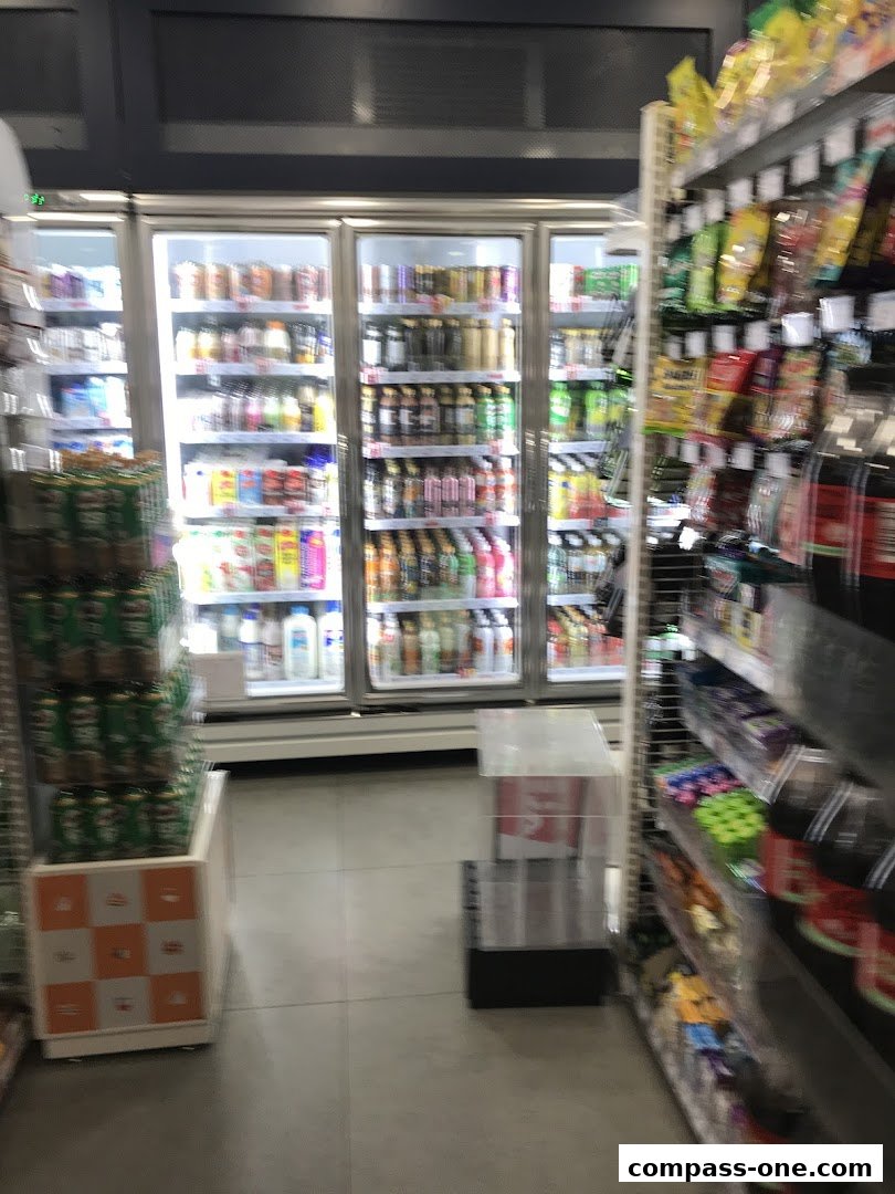 Interior view of a 7-Eleven convenience store with refrigerators and shelves stocked with drinks and snacks.