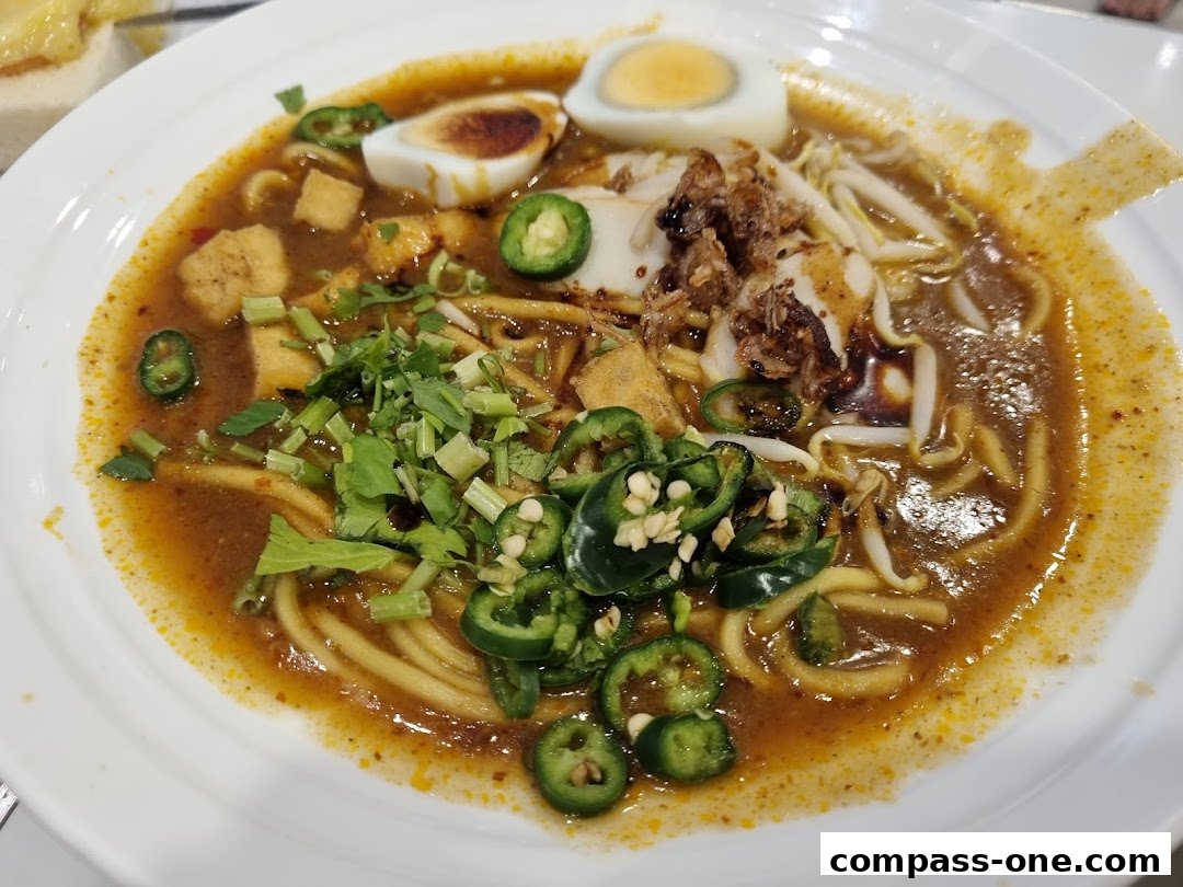 A close-up shot of a delicious bowl of Laksa with egg, chili, and bean sprouts.