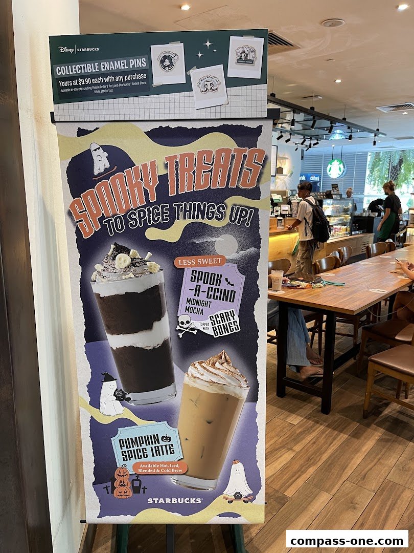 A Starbucks sign advertises Halloween-themed drinks and collectible enamel pins.