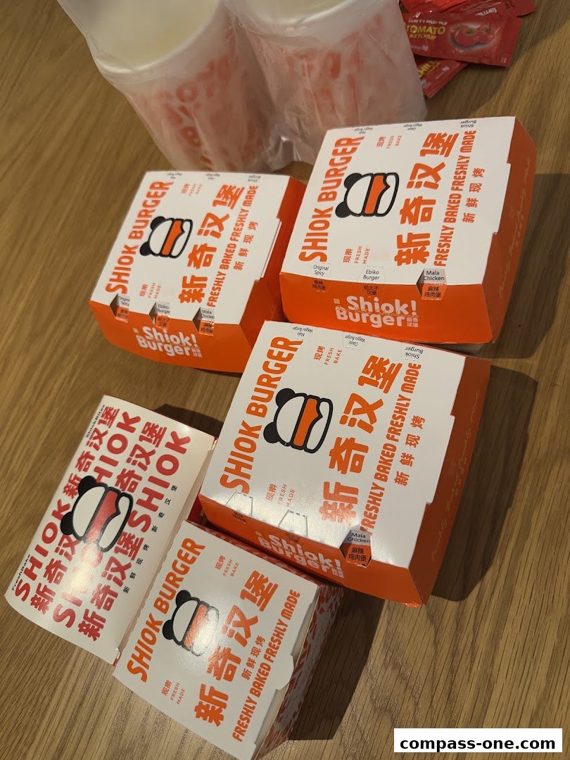 Several Shiok Burger boxes and takeout cups are arranged on a wooden surface.
