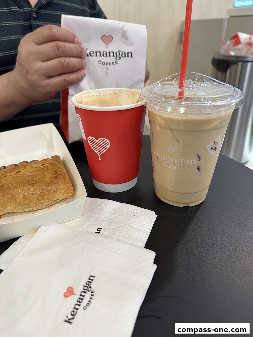 A table with Kenangan Coffee drinks, a pastry, and branded napkins.