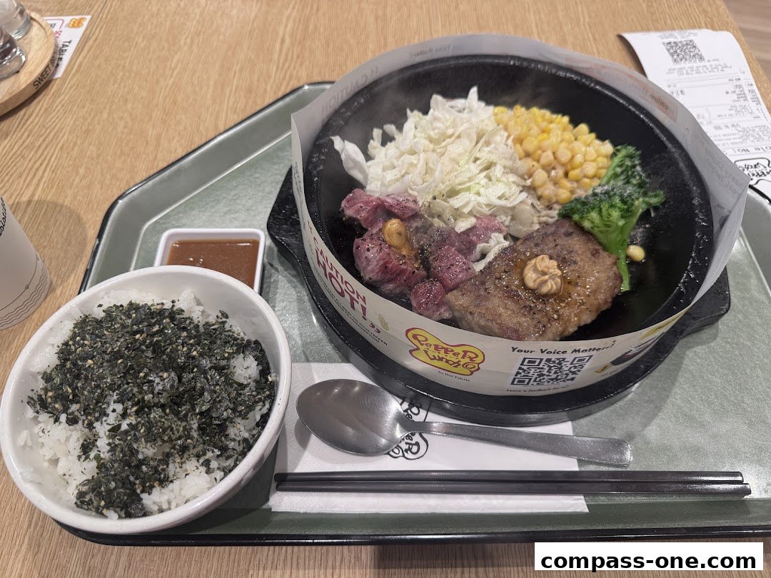 A sizzling hot plate meal with steak, vegetables, rice, and sauce.