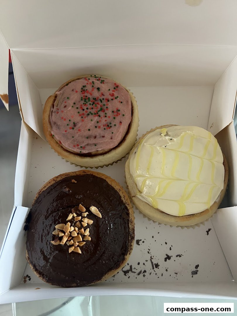 A box containing three delicious cinnamon rolls with different toppings.