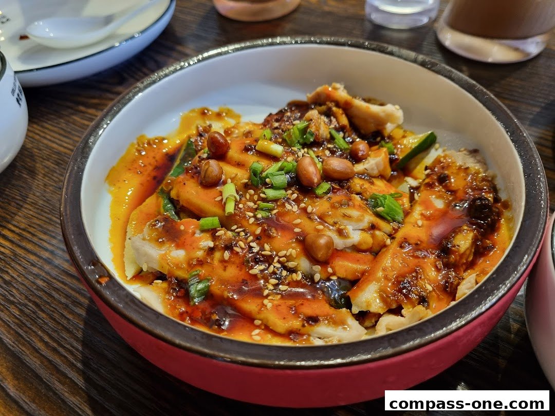 A close-up of a delicious bowl of grilled fish with chili oil, peanuts, and sesame seeds.