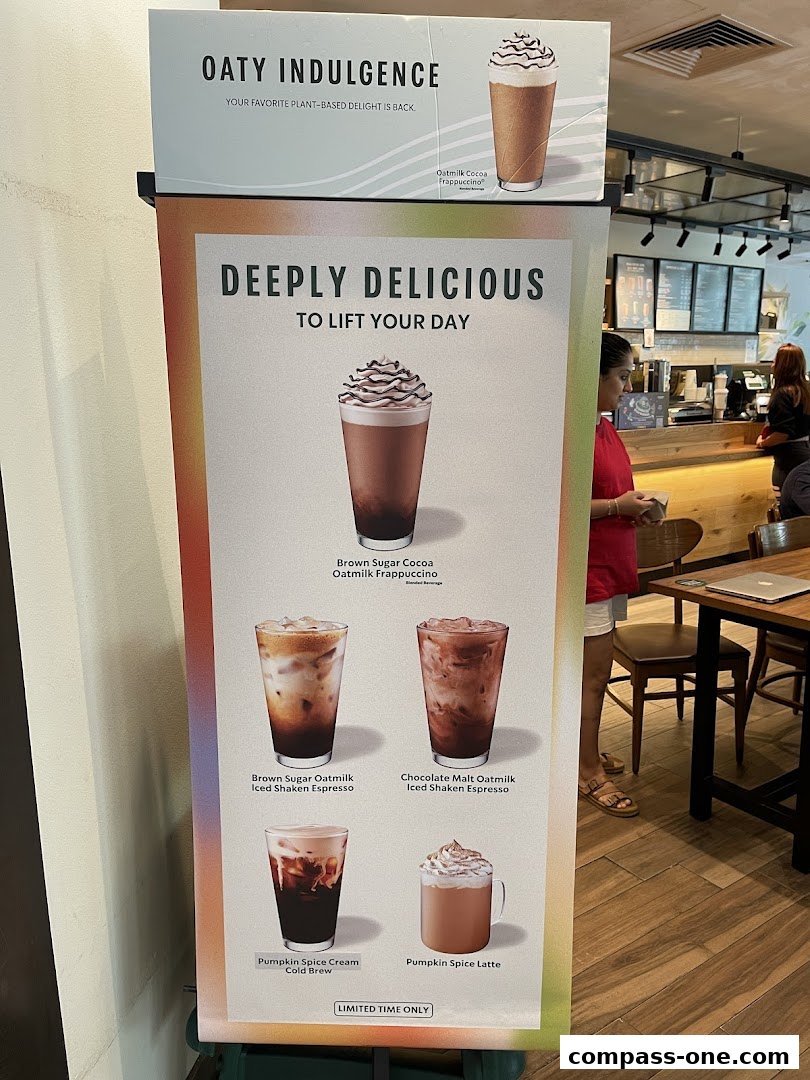 A promotional stand for Starbucks featuring various coffee drinks with oat milk and pumpkin spice.