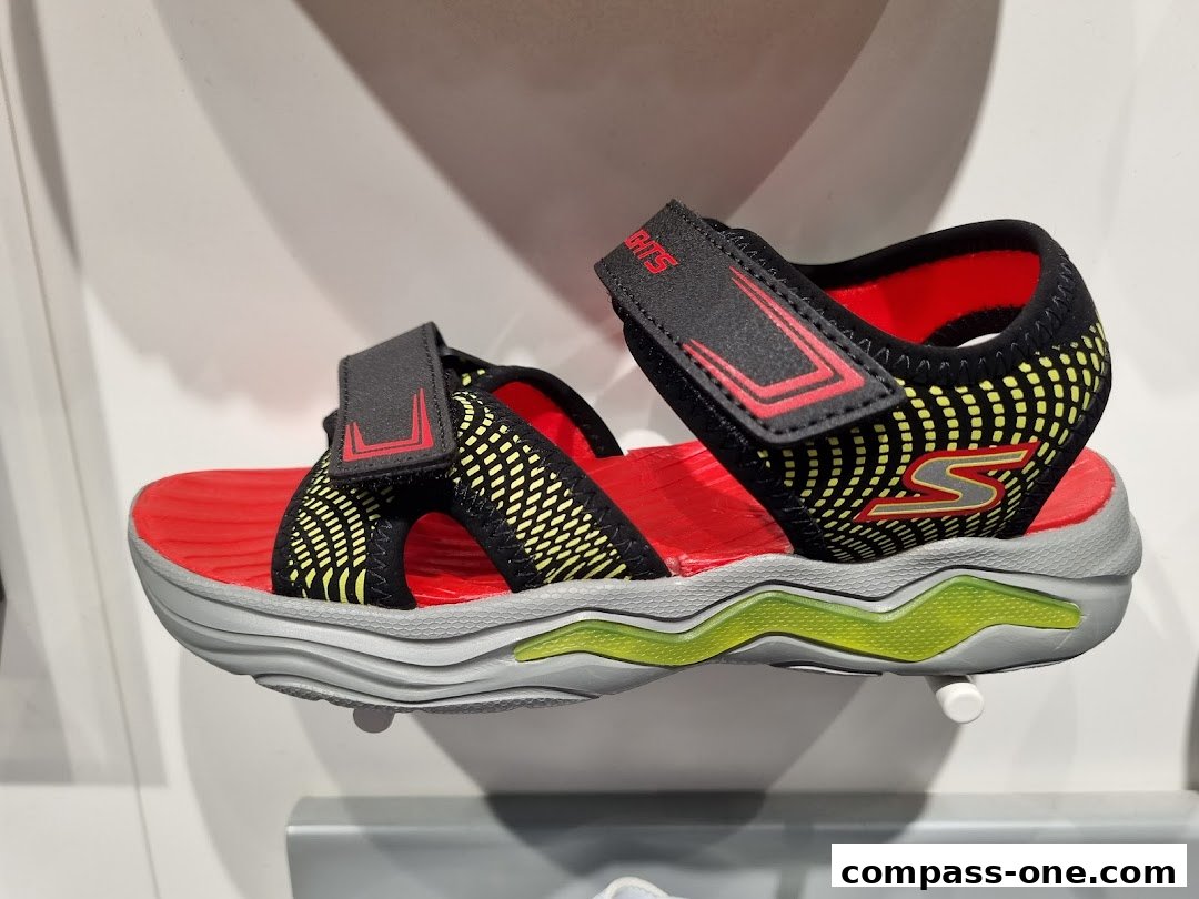 A close-up view of a red and black Skechers sandal with yellow accents and a light-up sole.