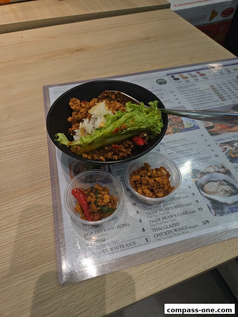 A close-up of a Thai dish with rice and side dishes, placed on a menu.