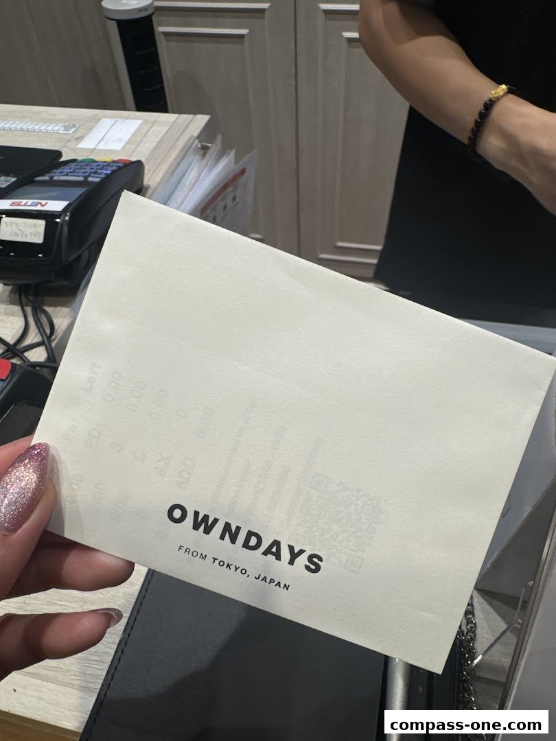 A hand holds a receipt from OWNDAYS, a glasses store.