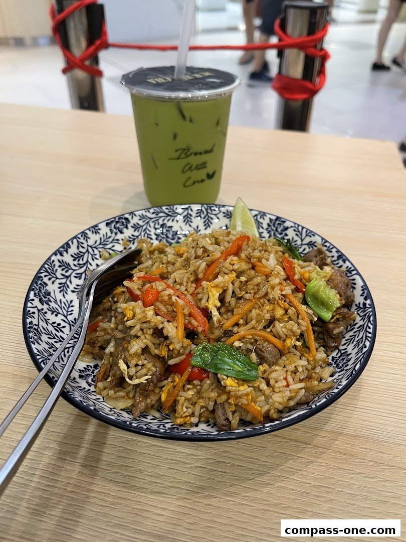 A plate of fried rice with beef and vegetables, served with a green drink.