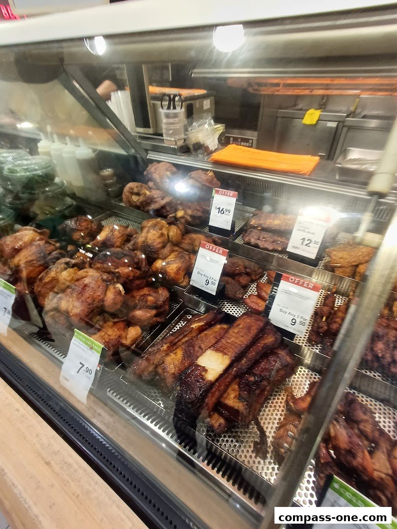 A display case filled with various roasted chickens and ribs, with price tags and offers visible.