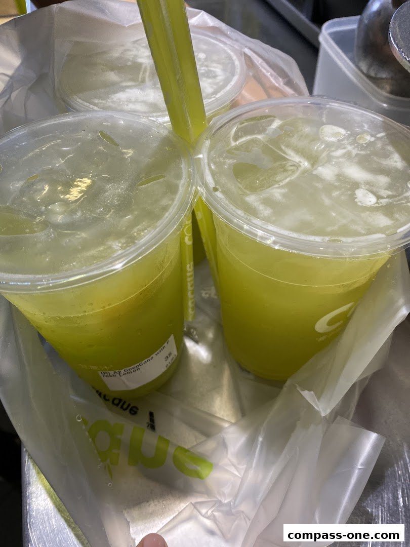 Close-up of refreshing sugarcane drinks with ice and straws in plastic cups.