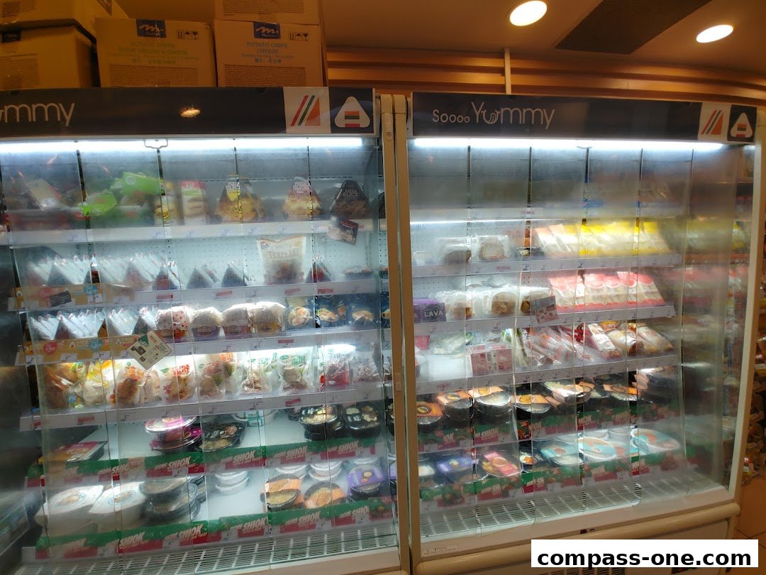 Refrigerated display cases filled with various pre-packaged food items at a 7-Eleven store.