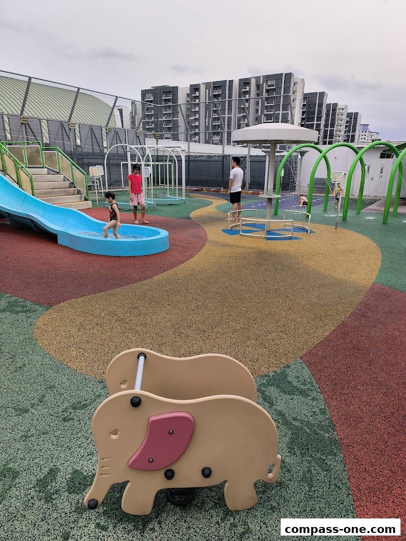 Children playing at a colorful outdoor water playground with slides and water features.