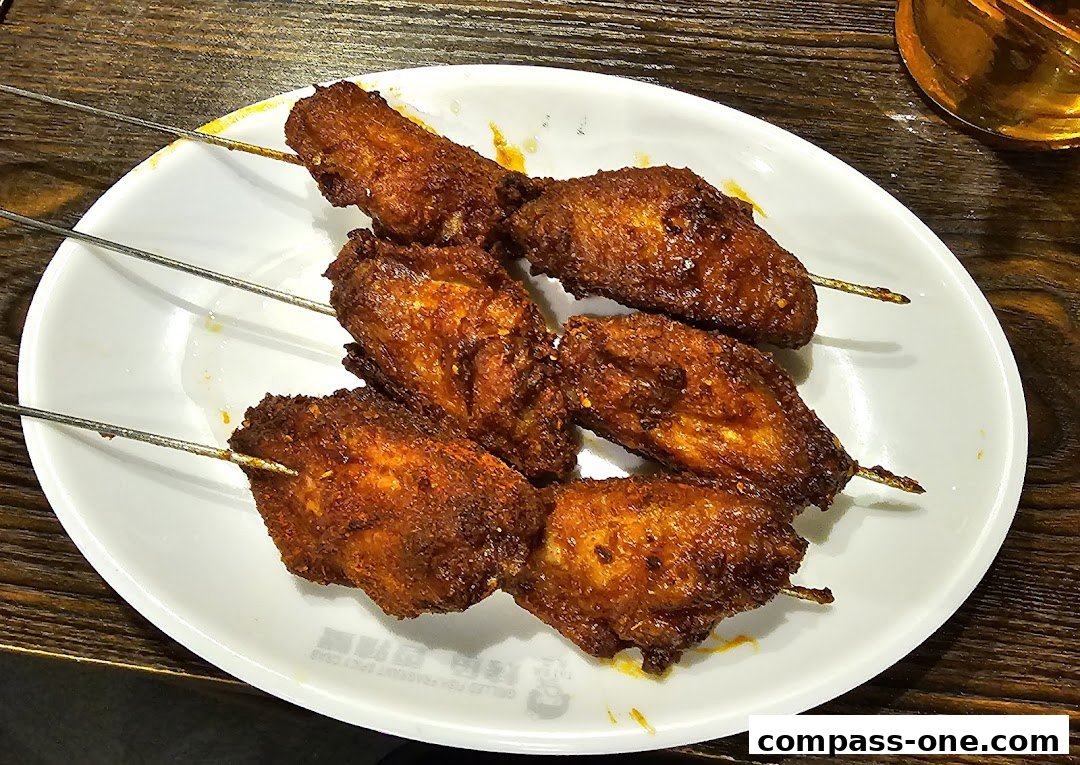 A plate of six grilled chicken wings on skewers, seasoned with spices.