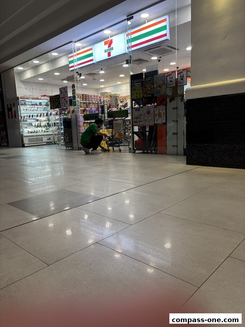 A 7-Eleven store entrance with a person cleaning the floor in front.
