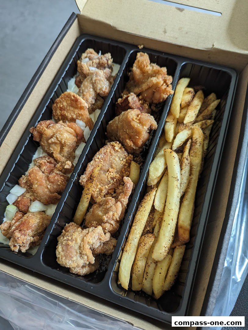 A takeaway box filled with crispy fried chicken pieces and seasoned french fries.