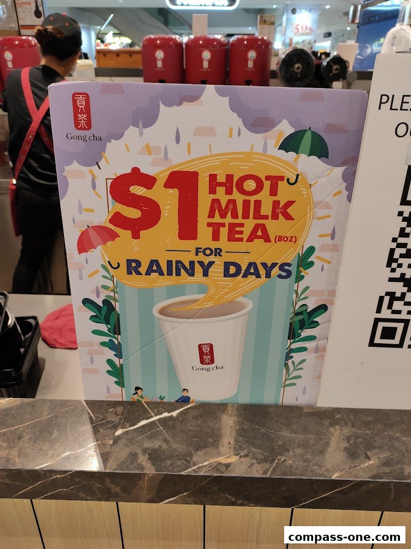 A promotional sign for Gong Cha offering $1 hot milk tea for rainy days.