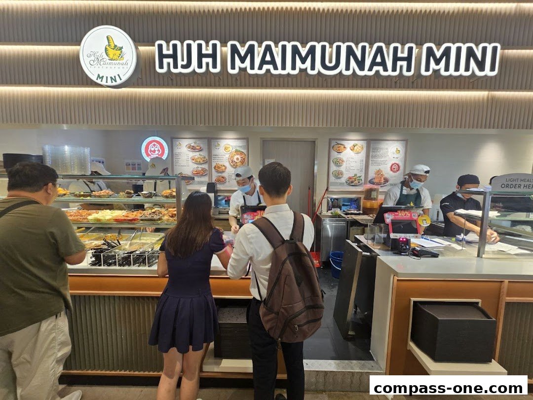 Customers ordering food at a counter with a display of various dishes.