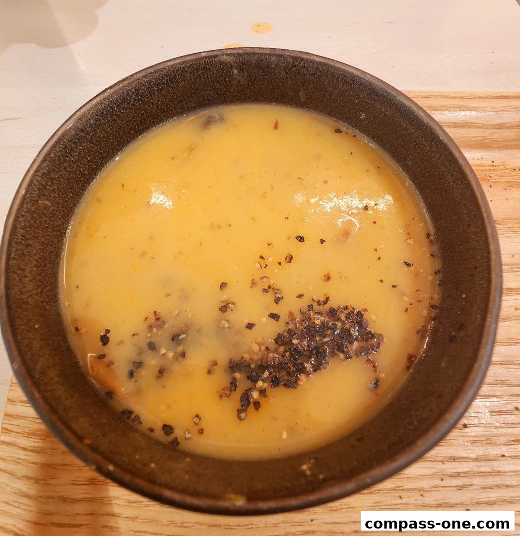 A close-up shot of a bowl of creamy soup topped with cracked black pepper.
